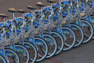 Benzer markalı bisikletlerin düzenli bir sıra görüntüsü, muhtemelen bisiklet paylaşımı veya kiralama servisinin bir parçası, kentsel bir ortamda asfalt bir alana park edilmiş, organizasyonu destekleyen, erişimi olan Kyiv, Ukrayna, 09-15-2024