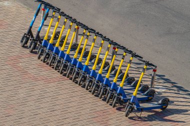 Ukrayna 'nın başkenti Kyiv' e uygun organize bir park alanı veya kiralama istasyonundaki ortak şehir ulaşımını temsil eden bir tuğla kaldırıma yerleştirilmiş elektrikli scooterların tanıtım görüntüsü, 09-15-2024