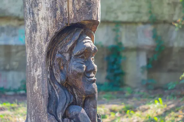 Doğal, parkvari bir ortamda biçimlendirilmiş insan yüzünün eskimiş, parlatılmış taş veya metal bir heykeli, dinginlik ve zamansızlık yayıyor Kyiv, Ukrayna, 09-15-2024