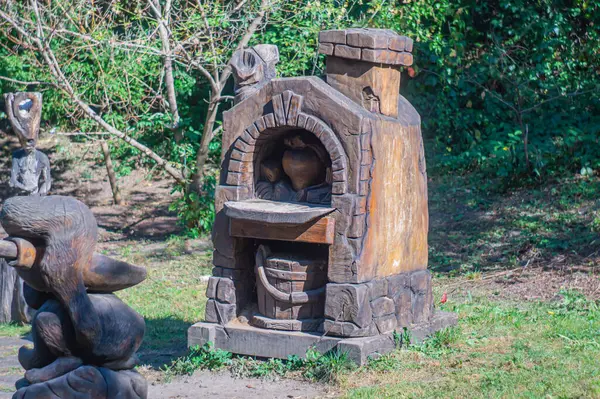 Kyiv, Ukrayna, 09-15-2024 toplantıları için uygun doğal bir alanda ahşap ve taştan yapılmış sade, heykel süslemeli bir fırın.