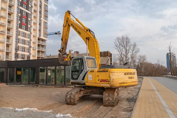 Aktif bir inşaat sahasında sarı kazıcı, güvenlik önlemleri mevcut ve yakınlardaki konut veya karışık kullanımlı yapılar Kyiv, Ukrayna, 09-15-2024