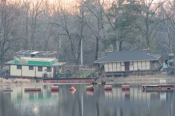 Kırsal bir rıhtım ve iki katlı bir binayla sakin bir su manzarası, rahatlama, dinlenme ve deniz manzarası etkinlikleri veya Kyiv, Ukrayna, 09-15-2024 için ideal bir liman olduğunu ima ediyor.