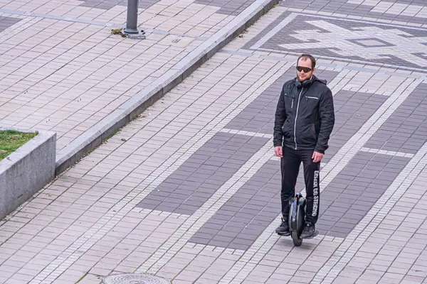 Kendi dengesini sağlayan scooter kullanan bir adam, yaya sokak imajı boyunca ilerliyor. Çevre dostu modern ulaşım araçları Kyiv, Ukrayna, 09-15-2024