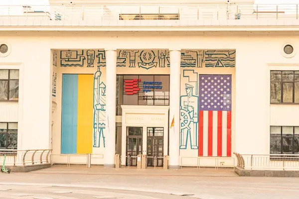 Görüntü, uluslararası temalı modern bir ofis binasını gösteriyor, büyük camlı, mavi-sarı bir afiş, muhtemelen ulusal bir bayrak, ve vatansever bir Amerikan f 'i Kyiv, Ukrayna, 09-15-2024