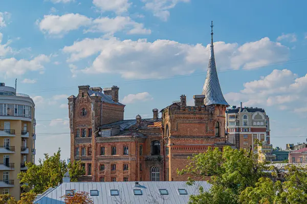 Kule ve sivri uçlu çatı gibi mimari unsurlara sahip eski, kırmızı tuğla bir binanın havadan görüntüsü, şehir merkezinde veya kentsel alanda yer alıyor. Mimar Kyiv, Ukrayna, 09-15-2024