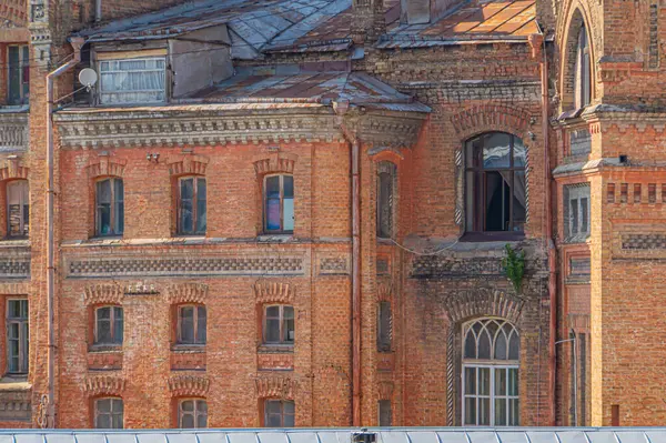 Kyiv, Ukrayna 'nın gri gökyüzü ile zıt yaş belirtileri gösteren, kemerli camları ve süslü süslemeleri olan eski bir Avrupa tuğla binası, 09-15-2024