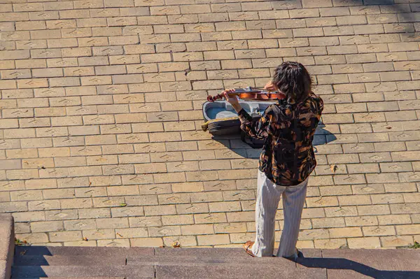 Resim, müzik eğitimi, sanatsal yetenek ve kişisel ifade temaları olan Kyiv, Ukrayna, 09-15-2024 'ü sembolize ederek, tutkuyla keman çalan bir kişiyi gösteriyor.