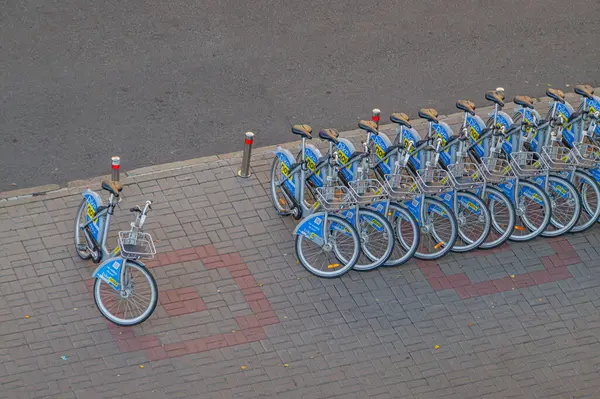 İyi korunmuş bir alandaki hizalanmış mavi bisikletlerin resmi, muhtemelen bisiklet paylaşım programının bir parçası veya popüler bisiklet durağı Kyiv, Ukrayna, 09-15-2024