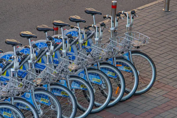 Görüntü beyaz bisikletli bir bisiklet paylaşım istasyonunu gösteriyor. Mavi renkli Kyiv, Ukrayna, 09-15-2024