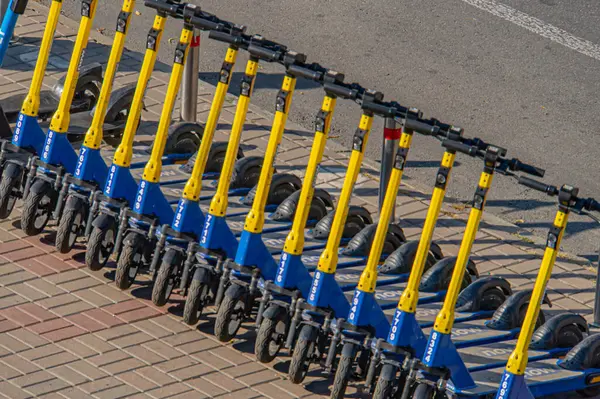 Görüntü, büyük olasılıkla kiralık veya satışta, canlı renkler ve kentsel tra Kyiv, Ukrayna, 09-15-2024 ile ilişkili üniforma düzeninin yer aldığı mavi ve sarı bir sıra scooter veya mini motosiklet gösteriyor.