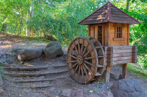 Doğada taştan bir merdivende ahşap bir kulübe, yakınlarda klasik bir araba tekerleği, yeşilliklerle çevrili cennet gibi bir kaçış imkanı sunuyor ve Ukrayna, Kyiv, Ukrayna, 09-15-2024