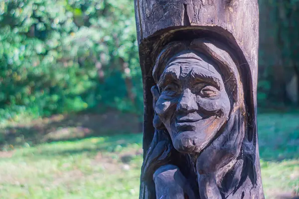 Heykel, dingin bir gülüşü olan yaşlı bir kadının ayrıntılı, ahşap heykelinin yer aldığı açık hava kurulumunun görüntüsü heykel, yaşı ve bilgeliği gösteriyor ve Enga Kyiv, Ukrayna, 09-15-2024