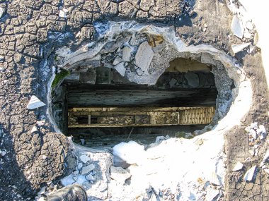 Görüntü, patlamanın ya da tahribatın ardından, beton yüzeyde açık tahta kirişlerle büyük bir delik açıldığını gösteriyor. Sahne, sebze eksikliğine bağlı olarak kentsel ya da endüstriyel bir yerde çekiliyor.