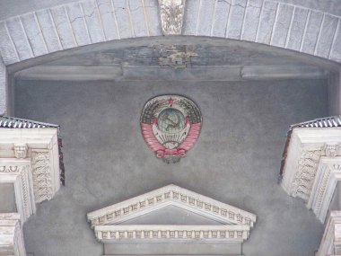 Görüntü, olası hükümet veya kurumsal nüfuza sahip resmi ve tarihsel bir binanın iç görünümünü gösteriyor. Fotoğraf, tavana ve kemer yoluna karmaşık bir açıyla bakıyor.