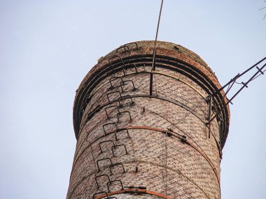 Görüntü, bakım ve tırmanma merdiveni olan uzun, dar bir bacayı gösteriyor. Tuğla yapı çeşitli yüksekliklerde metal parantezlere sahiptir, muhtemelen destek ekipmanları için.