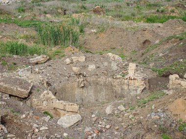 Büyük kaya oluşumları ve enkazları olan kayalık, seyrek bitki örtülü bir arazinin havadan görünüşü düz ve farklı zemin dokusu nedeniyle merkezi bir kazı alanı veya taş ocağı dikkate değerdir.