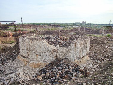 Hasarlı endüstriyel inşaat alanı yapısının enkaz, kısmen kazılmış katmanlar ve gelişmemiş arazinin etrafındaki arka plan muhtemel endüstriyel tesisleri ya da elektrik santrallerini gösteriyor.