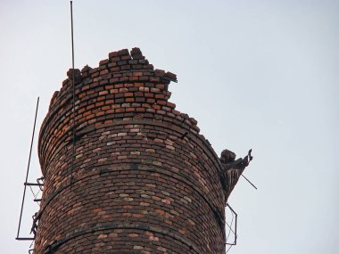 Kısmen çökmüş kırmızı turuncu bir baca ya da gökyüzüne bakan bir kule görüntüsü.