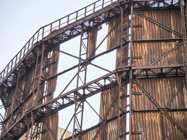 Görüntü eski, paslı bir endüstriyel köprü ya da çürümekte olan bir üst geçit yapısını gösteriyor.