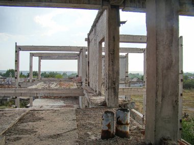 Harap olmuş beton bir yapının görüntüsü, kısmen çökmüş, kırsal ya da endüstriyel alanda bitkisel büyüme ve yıpranma belirtileri gösteriyor.