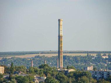 Görüntü bacaları olan bir endüstriyel tesis gösteriyor, bitişik kentsel yerleşim alanları...
