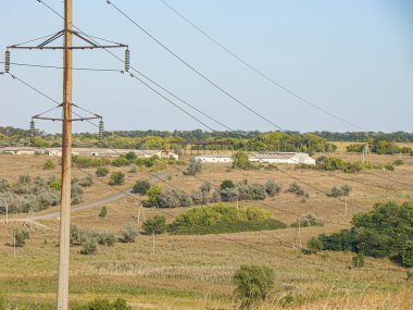 Elektrik altyapısı, dağınık bitki örtüsü, yol ve çiftlik yerleşimleriyle temiz gökyüzü altında kırsal alan