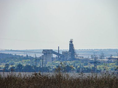 Çimento fabrikası veya taş ocağı, dijital kaplama, endüstriyel yapılar, bacalar, yüksek yığınlar, bulutlu gökyüzü, yeşillik, ağaçlar, gerçekçi stil, dijital manipülasyon