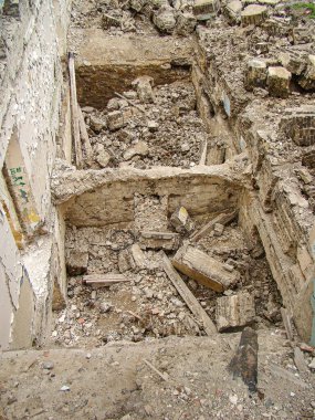 Görüntü, patlamadan sonraki yıkıcı bir sahneyi gösteriyor. Büyük bir delik ve dağınık enkaz gösteriyor. Çevrede ciddi bina hasarları var.