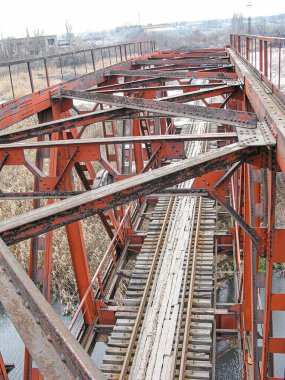 Eski, paslı bir metal yapının yakın görüntüsü, açık havada gökyüzü, ayrıntılı metal işçiliği, görünür perçin ve diş telleri, düşük açılı perspektif