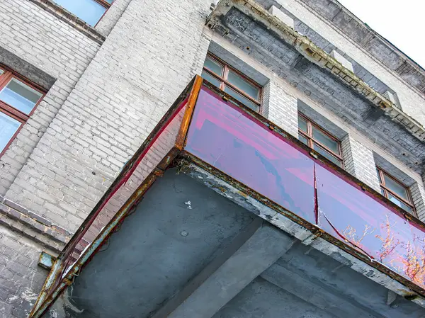 Görüntü, iç cephesi hasarlı, paslanmış metal panelleri olan harap olmuş beton bir bina gösteriyor. Hava durumu binası terk edilmiş veya bakımsızlığa uğramış olabilir.