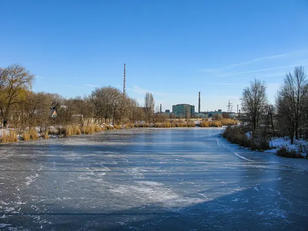 Kış ya da sonbahar aylarında çekilen donuk buz desenli su kütlesi. Arka plandaki endüstriyel yapılar muhtemelen kamerasız çekilecek.