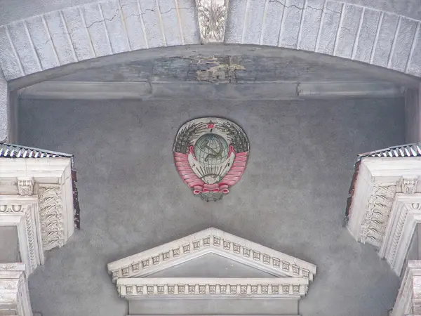 Görüntü, olası hükümet veya kurumsal nüfuza sahip resmi ve tarihsel bir binanın iç görünümünü gösteriyor. Fotoğraf, tavana ve kemer yoluna karmaşık bir açıyla bakıyor.