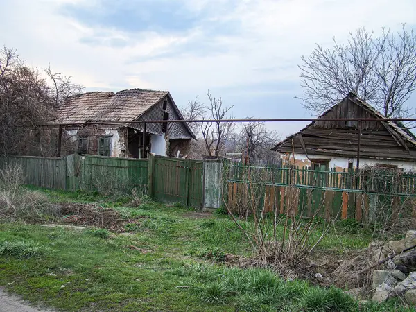 Doğu Avrupa tarzı evleri olan terk edilmiş, eski yerleşim yerlerini tasvir eden resimler, evlerin çatıları yıpranmış, ahşap duvarları kısmen yeşil bir kapı ya da çit zeminiyle kaplanmış.,