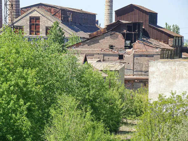 Görüntü, çok katlı ve düz çatıları olan terk edilmiş bir sanayi binasını tasvir ediyor. Kayıp fayanslar gibi hasar, kaza ya da ağır hasar nedeniyle son zamanlarda hasar gördüğünü gösteriyor.