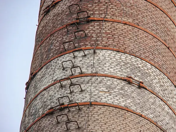 Dayanıklılık ve dayanıklılık için tasarlanmış sağlam bir endüstriyel baca, yapının bir kısmı boyunca yatay metal çubuklar güvenlik özellikleri veya destek arka planı olabilir.