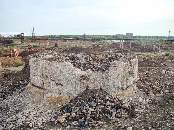 Hasarlı endüstriyel inşaat alanı yapısının enkaz, kısmen kazılmış katmanlar ve gelişmemiş arazinin etrafındaki arka plan muhtemel endüstriyel tesisleri ya da elektrik santrallerini gösteriyor.