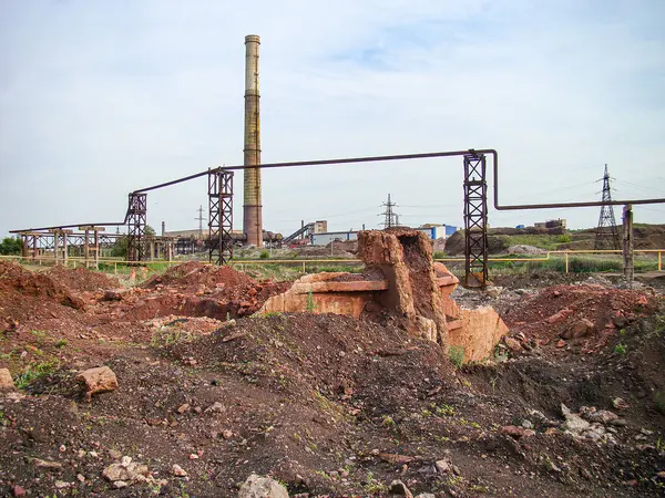 Görüntü, arka planda inşaat veya yıkım çalışmalarını, muhtemelen elektrik santralleri veya ağır tesisleri öneren bir sanayi bölgesini resmediyor.