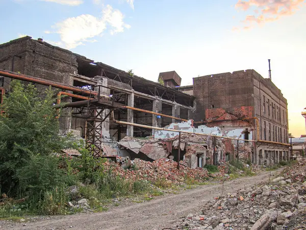 Terk edilmiş, harap bir sanayi binası çatısı ve çökmüş tuğla işi, muhtemelen gün doğumunda ya da batımında, enkaz etrafa saçılmış, içinde bitki örtüsü büyüyen, ve yol gösteren...