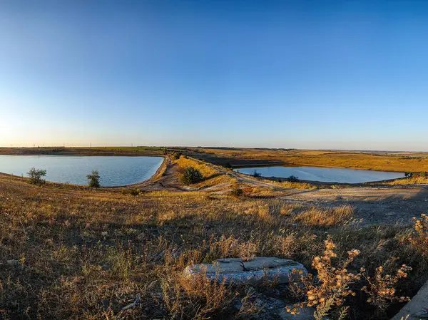 Sakin, izole bir yer. Suyun sakin bir vücudu var. Sıcak gündoğumu yansıtan renkler. Kuru arazi ekosistemindeki kuru ot ve bitki örtüsünü gösteriyor.