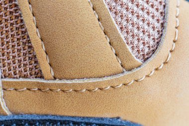 Kahverengi deri ayakkabı dikişlerinin yakın plan görüntüsü, yumuşak ışıklandırılmış derinlikteki kaliteli işçilik.