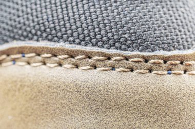 Lüks ayakkabı yapma detaylarını ön plana çıkaran yakın plan fotoğraf, bulanık bir arka plana karşı ayakkabıya dikişler vurgulanıyor.