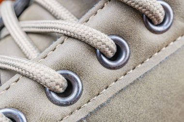 Dayanıklı, muhtemelen su geçirmez bir ayakkabının yakın plan fotoğrafı dayanıklı bağlama sistemi ve metal gözbebekleri, açık hava aktiviteleri veya sert koşullar için uygun