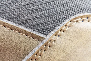 Mobilya parçasına yüksek kaliteli dikişlerin detaylı bir yakın plan çekimi, muhtemelen bir sandalye ya da sehpa işçiliği ve kumaş ile tasarım karşıtlığı üzerine vurgu