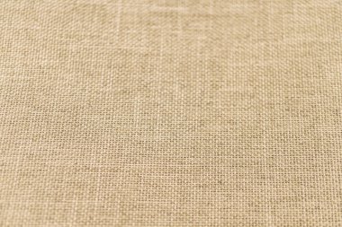 Yumuşak desenli yüzeyi olan, doğal tonlu, yüksek kaliteli bir kumaşın yakın plan görüntüsü, muhtemelen ev eşyaları, moda aksesuarları veya iç tasarım pazarlama malzemelerinde kullanılıyor.