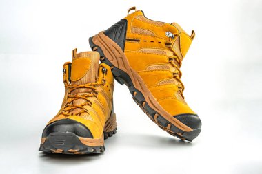 Sağlam inşaat ve sağlam bağlama sistemlerine sahip yüksek kaliteli yürüyüş botlarının görüntüsü, üzerinde hardal veya sarımsı tonların karışımı var, muhtemelen açık hava spor malzemeleri reklamı için.