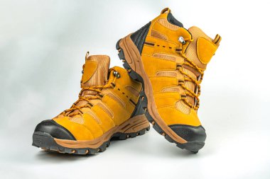 Görüntü, açık giyim pazarlaması için tarafsız bir arka plana vurgulanmış sağlam bağcıklı ve sağlam tabanlı parlak hardal yürüyüş ayakkabılarını gösteriyor.