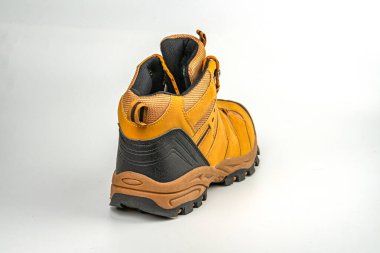 Resim tek bir yürüyüş botu gösteriyor, kahverengi ve siyah, traksiyon tabanlı, engebeli araziler için tasarlanmış tasarım yukardaki bağcıkları içeriyor ve dış etkinlikler sırasında dayanıklılık için güçlendirilmiş alanları içeriyor