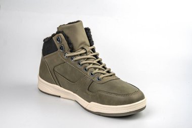 Görüntü, zeytin yeşili üst, siyah ayak parmağı kutusu ve eşsiz bir iz bırakan beyaz tabanlı yüksek tepeli bir spor ayakkabıyı gösteriyor.