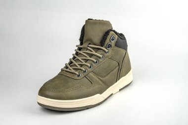 Görüntü, yeşil ve gri renkli, muhtemelen deri ve süetten yapılmış yüksek topuklu bir spor ayakkabıyı gösteriyor. Ayakkabı bağcıkları kalın, iyi yol tutuşu için kalın ve askeri esinlenilmiş ayakkabılar ile dayanıklı görünüyor.