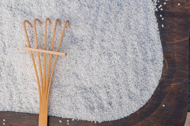 Koyu arkaplanda beyaz tozla çırpılmış ahşap bir çırpıcının yakın plan görüntüsü, muhtemelen mutfak hazırlığını ya da fikir karışımını sembolize ediyor. Odak ve zarafet üst düzey mutfak gereçleri ya da yemek pişirme kabını işaret ediyor.